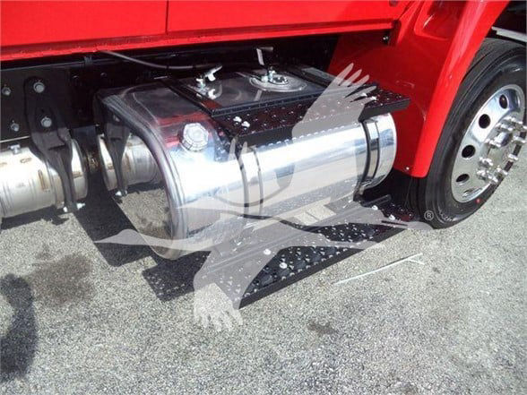 Truck fuel tank and undercarriage visible next to a red cab, with chrome fuel tank and steps.