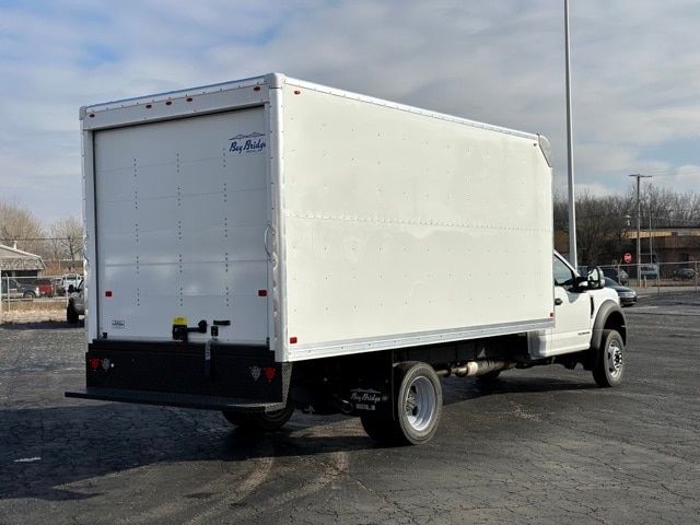 Ford F-550 box truck with white cargo box, rear doors closed, in a parking lot.