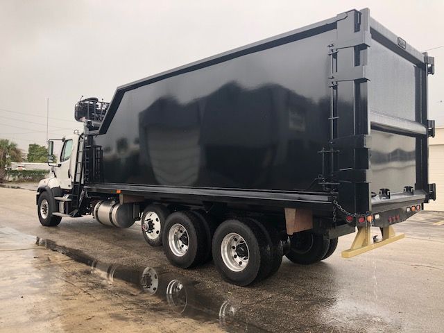 Truck side view of a 2019 Freightliner 114SD grapple dump truck with a black dump body and chrome wheels.