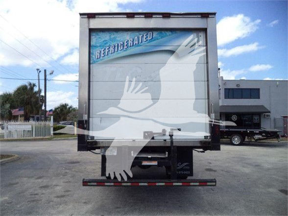 Rear view of a refrigerated box truck with raised metal doors, stock number 26199R, light blue sky, and a white graphic over the door.