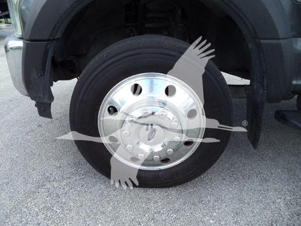 Wheel of a tow truck with chrome hub and black tire; partial fender above, no legible labels visible on the wheel.