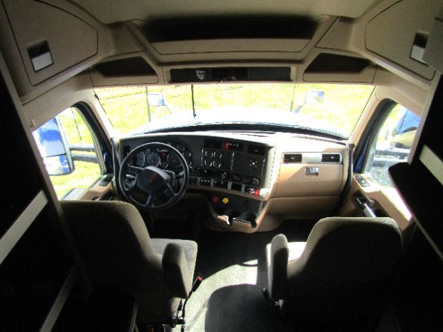 Kenworth T680 cab interior showing dash, steering wheel, gauges, and front seats.