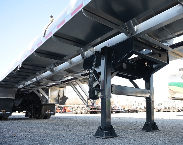 Trailer undercarriage with aluminum vacuum trailer legs and support beams, showing ground clearance and frame details.