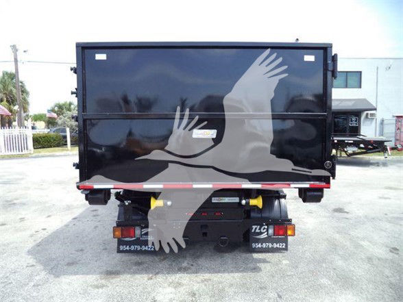 Isuzu NRR truck rear view with black dump body and yellow hitch pins, logo decal on tailgate, license plate area, and TLC rear lights.