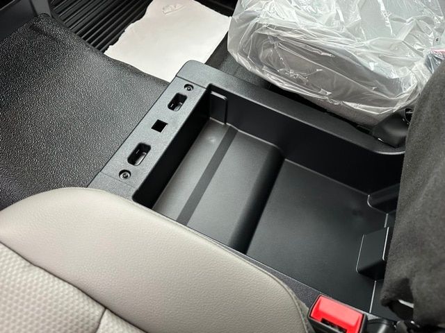 Centre console of a 2022 Ford F-550 with cup holder area and small storage compartments visible; plastic protective wrap on seat or cargo in background.