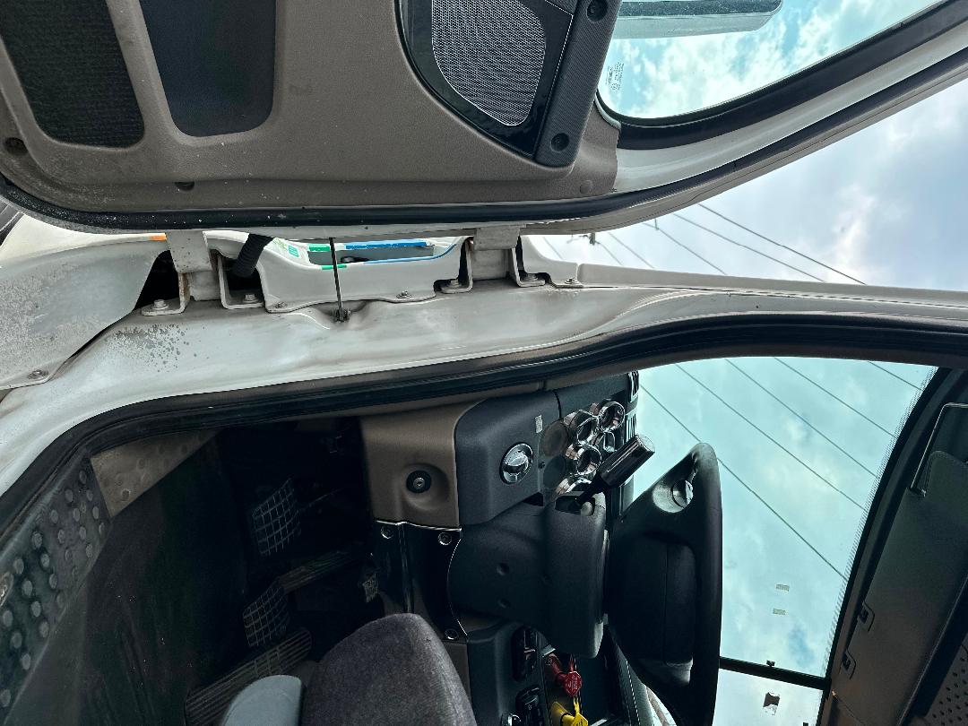 Dashboard and open sleeper cab area of a 2011 Freightliner Cascadia with the overhead sun visor and steering wheel visible.