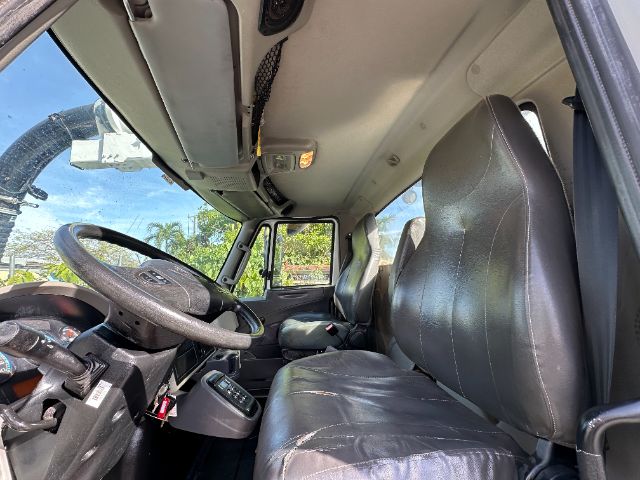 Interior cab of 2013 International 7500 vacuum truck showing steering wheel, dashboard, driver and passenger seats, and overhead controls.