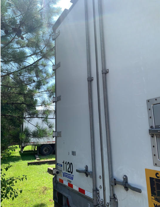 Rear view of a white Vanguard VXP trailer with doors closed, stock number 1120, showing rear bumper and latching hardware.