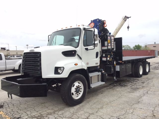 Truck with a knuckle boom crane mounted on the bed. Cab and front grille visible. Crane equipment and controls mounted behind cab.