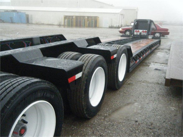 LarBoard view of a Talbert 55SA flatbed trailer showing multiple axles and wheels; no visible text legible on the deck in this angle.