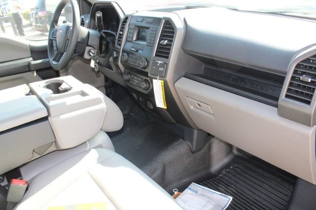 Truck interior showing front seats, center console, steering wheel, dashboard, and gear shifter. Visible text on the dashboard area includes typical Ford controls and a yellow tag hanging from the lower dash.