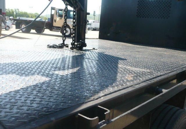 Freightliner M2 equipment trailer deck with metal diamond plate surface and chains.
