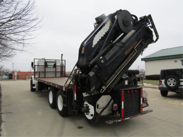 View of a 2003 Peterbilt 330 boom truck with a folded hydraulic crane on a flatbed trailer, seen from rear-left angle.