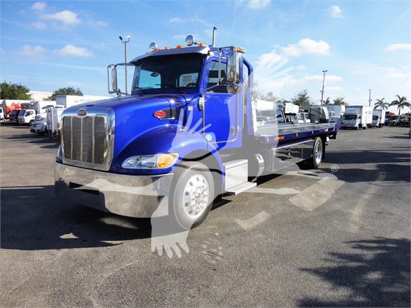 Peterbilt 337 tow truck in blue, front left side view with flatbed, stock number J32060 FM visible.