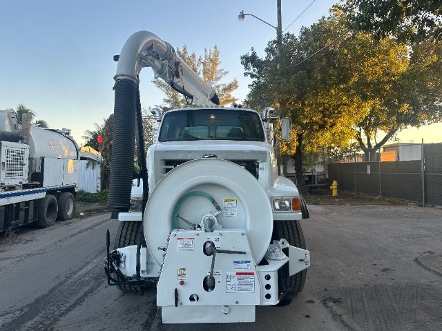 Front view of a white 2006 Sterling L8500 vacuum/garbage truck with a large circular drum and an articulating arm extending over the cab.