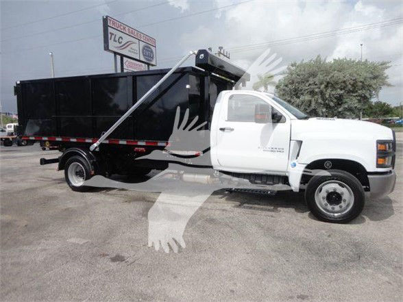 2013-2023 Chevrolet Silverado 5500HD dump truck with black bed and white cab, side marker and lettering faintly visible, dealership lot in background.