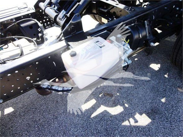Isuzu NPR HD chassis with coolant reservoir visible, plastic white coolant expansion tank mounted to frame with hoses and black chassis components.
