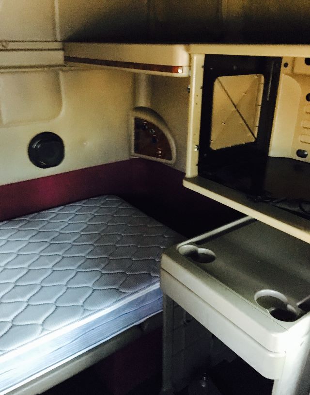 Interior sleeper cab of a 2007 International 9400I showing a single bed with quilted mattress, storage cabinet, and a microwave/combo unit in the cab area.