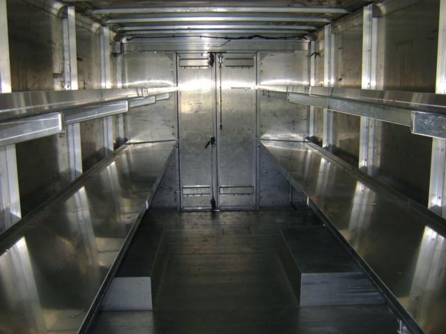 Interior of a metal Freightliner MT45 cargo area with aluminum shelving along both sides and a central aisle.