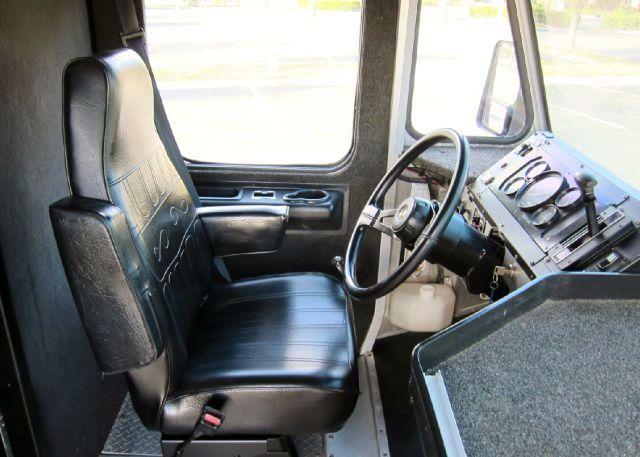 Truck cab interior showing driver seat and steering wheel of a 2005 Workhorse P42 step van with black vinyl seats and dashboard gauges.