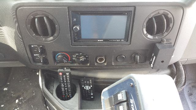 Dashboard view of a 2009 Ford E-450 bus showing a touchscreen display, circular air vents, climate controls, and a mounted remote control unit.