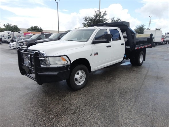 Ram 3500 dump truck white with utility bed and front grille guard, side view showing dual rear wheels and dump bed.
