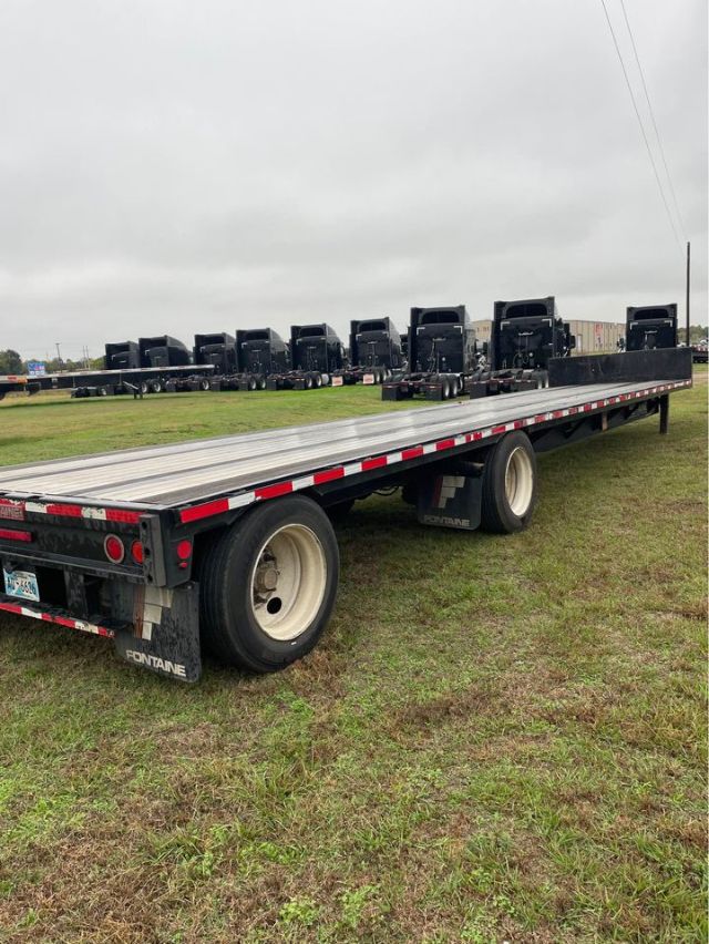 2019 Fontaine 48X102 Step Deck trailer showing long flatbed with multiple detachable gooseneck or loading ramps in the background.