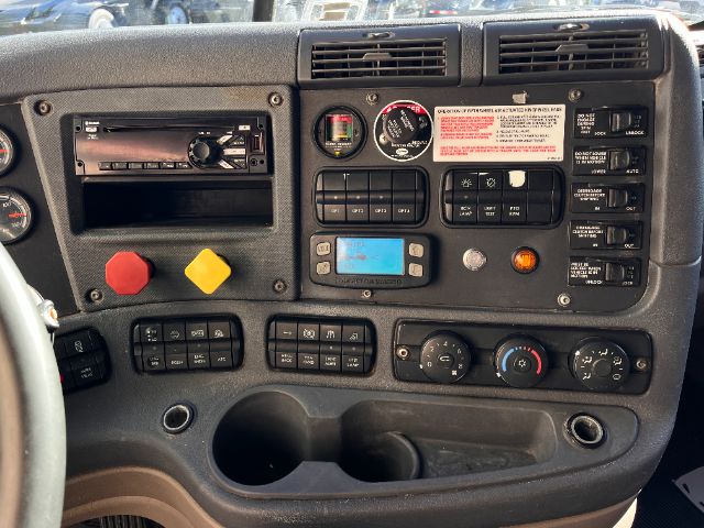 Dashboard of a Freightliner Cascadia 125 truck showing control panel, gauges, buttons, climate controls, and a digital display.