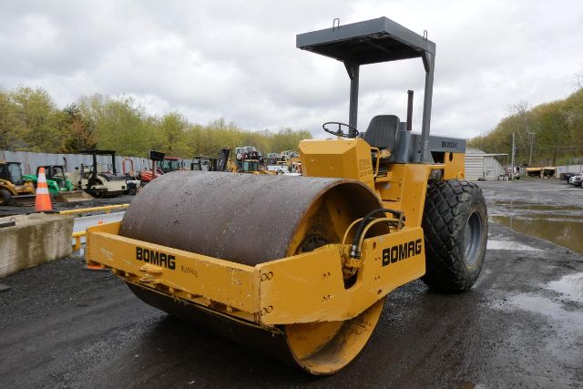 Bomag BW212D-2 vibratory roller showing large steel drum and operator seat with canopy, yellow paint, and branding Bomag.