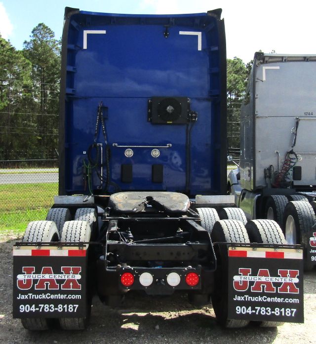 Back view of a blue 2020 Kenworth T680 truck cab and chassis with dual rear axles, fifth wheel, and mud flaps showing JAX Truck Center branding.