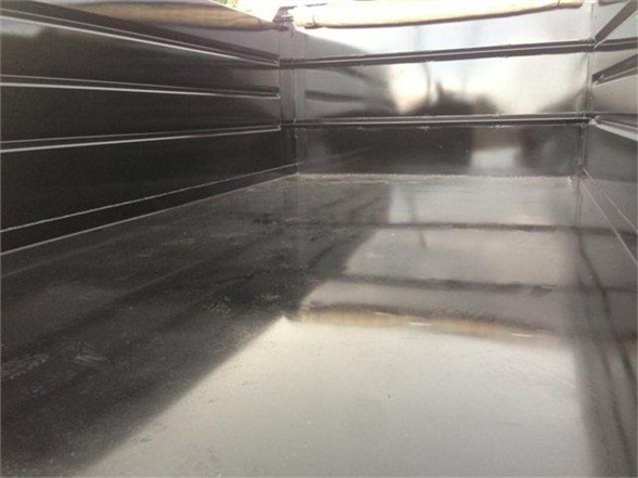Interior of a black dump body truck bed with reflective glossy floor and sidewalls. No visible text or labels inside.
