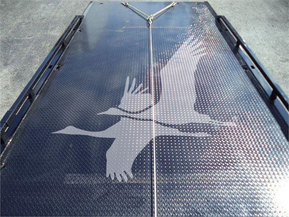 Platform bed with diamond plate surface and a graphic of a running or leaping animal silhouette on a Chevrolet Silverado 6500HD tow truck.