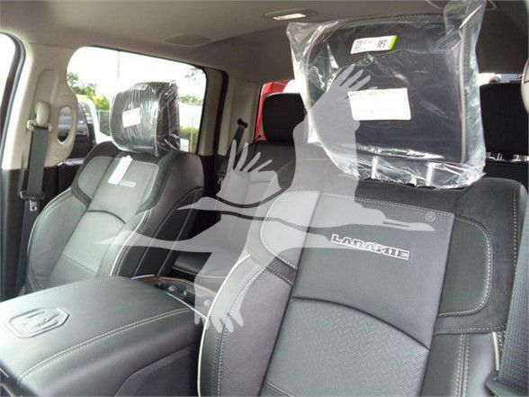 Ram Laramie interior seats with 'Laramie' embroidered on the front seat backrests, plastic-wrapped headrests, and center console visible.