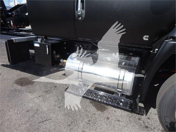Truck side view showing polished cylindrical fuel tank under the door of a 2023 International MV tow truck.