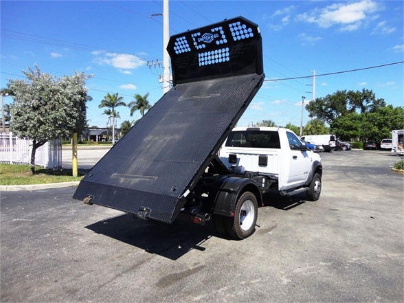 2024 Ram 5500 HD hooklift truck with raised bed in a parking lot showing rear plate and white cab.