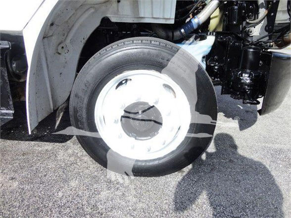 Flatbed truck wheel and front suspension of a 2015 Freightliner BUSINESS CLASS M2 106 showing wheel and tire with white steel rim and exposed suspension components.