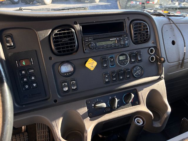 Dashboard of a Freightliner M2 cab showing various gauges, vents, radio, and control switches.