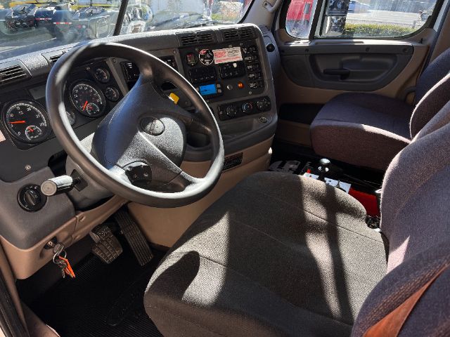 Dashboard and steering wheel of a 2020 Freightliner Cascadia 125 truck cabin with gray interior and driver seat.