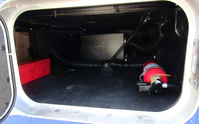 Kenworth T680 cargo area showing storage compartment with hoses and a red portable extinguisher mounted at right side.