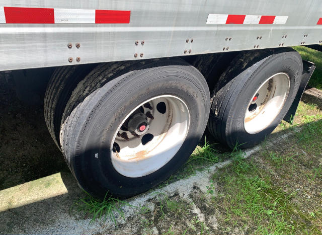 Dual rear trailer wheels with white rims and black tires under a Vanguard VXP utility trailer side panel with red/white reflective strips.
