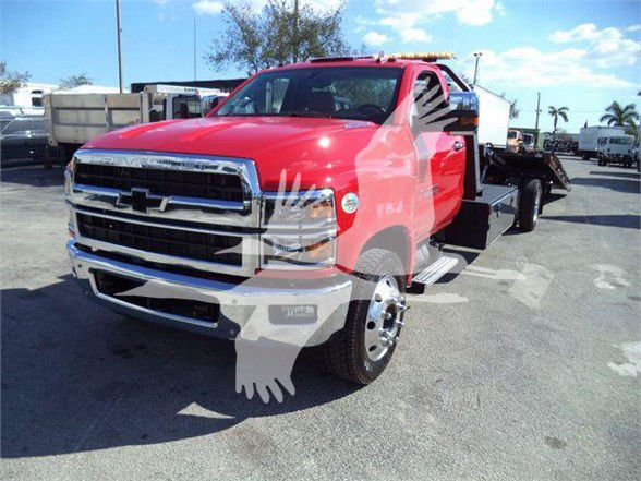 2023 Chevrolet Silverado 6500HD tow truck with red cab and flatbed visible.