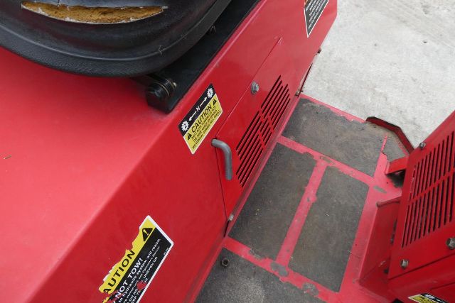 Close-up of red Steiner machine showing caution labels and a small gray handle on the side, with vents and a low-wheeled platform.
