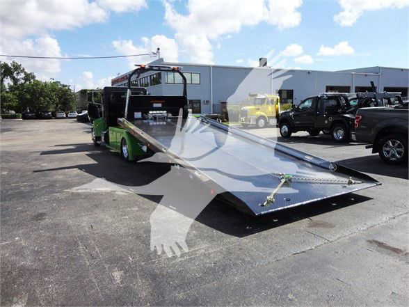 Peterbilt 337 tow truck with flatbed in a dealership lot