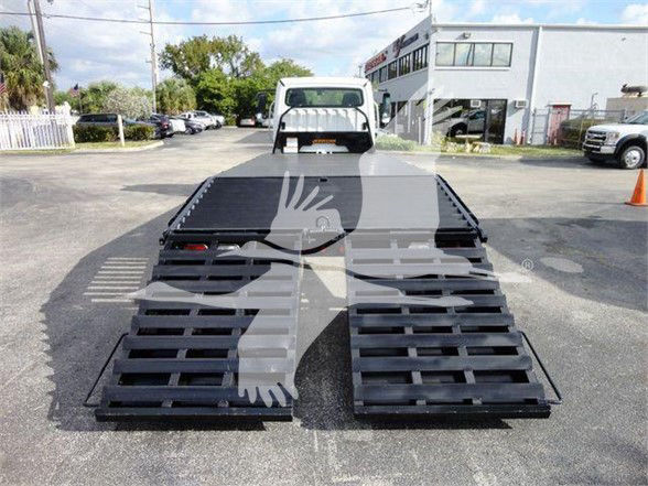 Freightliner BUSINESS CLASS M2 106 flatbed truck with dual ramps, front view in a dealership lot.