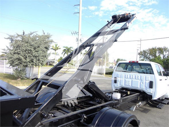 Truck chassis with a raised hydraulic bed hoist on a white Silverado 5500HD chassis cab, showing the lifting mechanism and rear section.