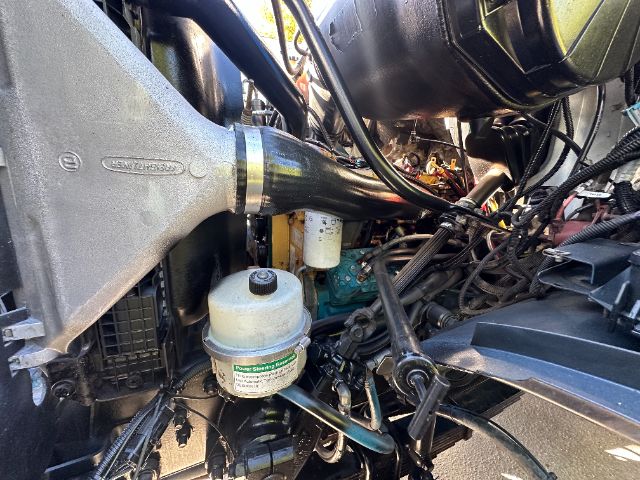Sterling L7500 vacuum truck engine bay showing coolant reservoir, air intake, and various hoses and wiring.