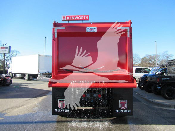 Kenworth T880 dump truck rear showing red bed and splash of white liquid on tailgate, with Kenworth logo and truck worx branding.