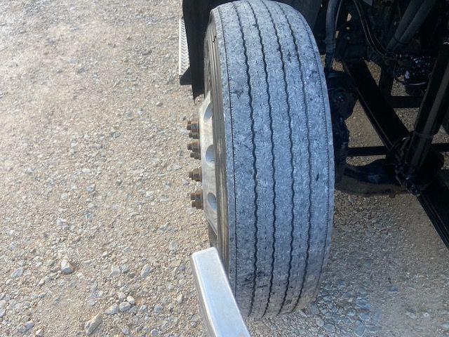 Truck front wheel showing dual rear axles and tire tread in a Mack CXU613 truck.