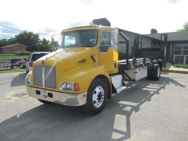 Kenworth T300 flatbed truck in yellow cab side view showing front grille and long flatbed.