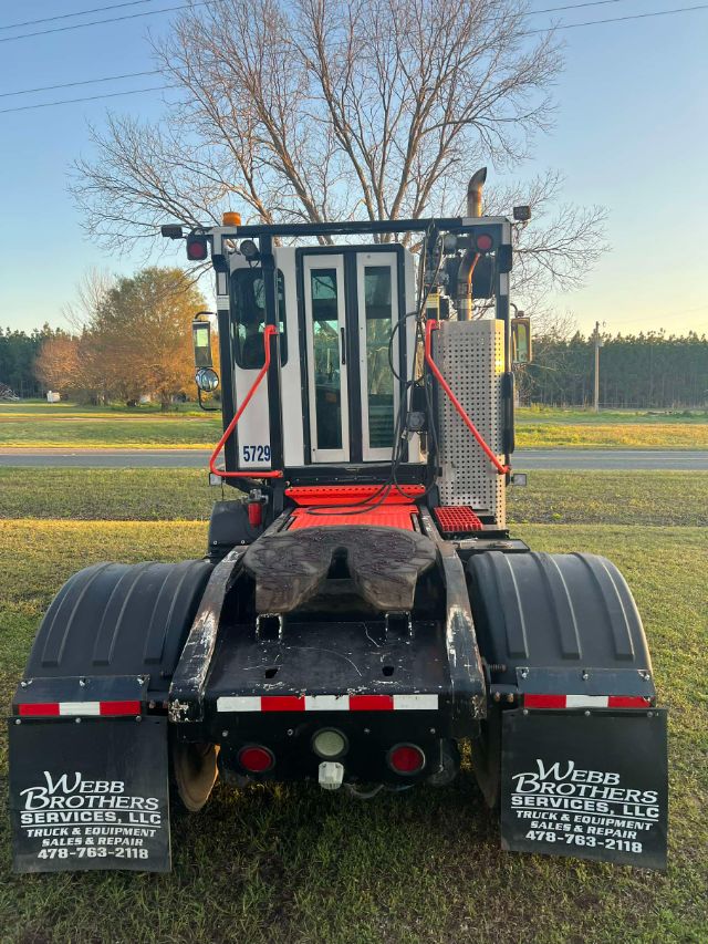 Rear view of a 2014 Tico Prospotter truck with fifth wheel, cab in center, black fenders, and Web Brothers mudflaps showing contact info.